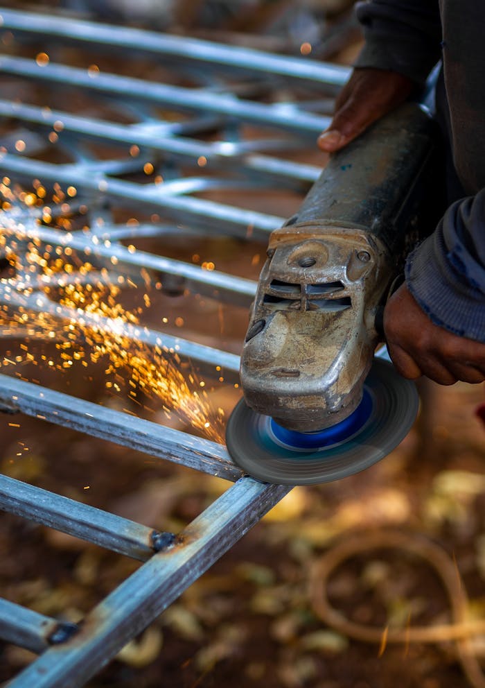 Close-up of a worker using a grinder on metal, creating a shower of sparks.